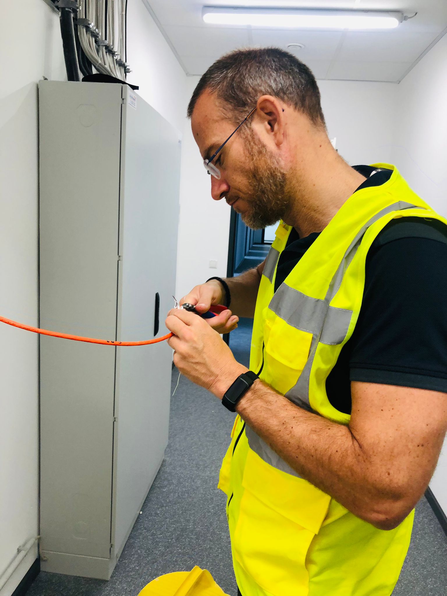 Onze monteur werkt aan de bekabeling in een patchkast op locatie