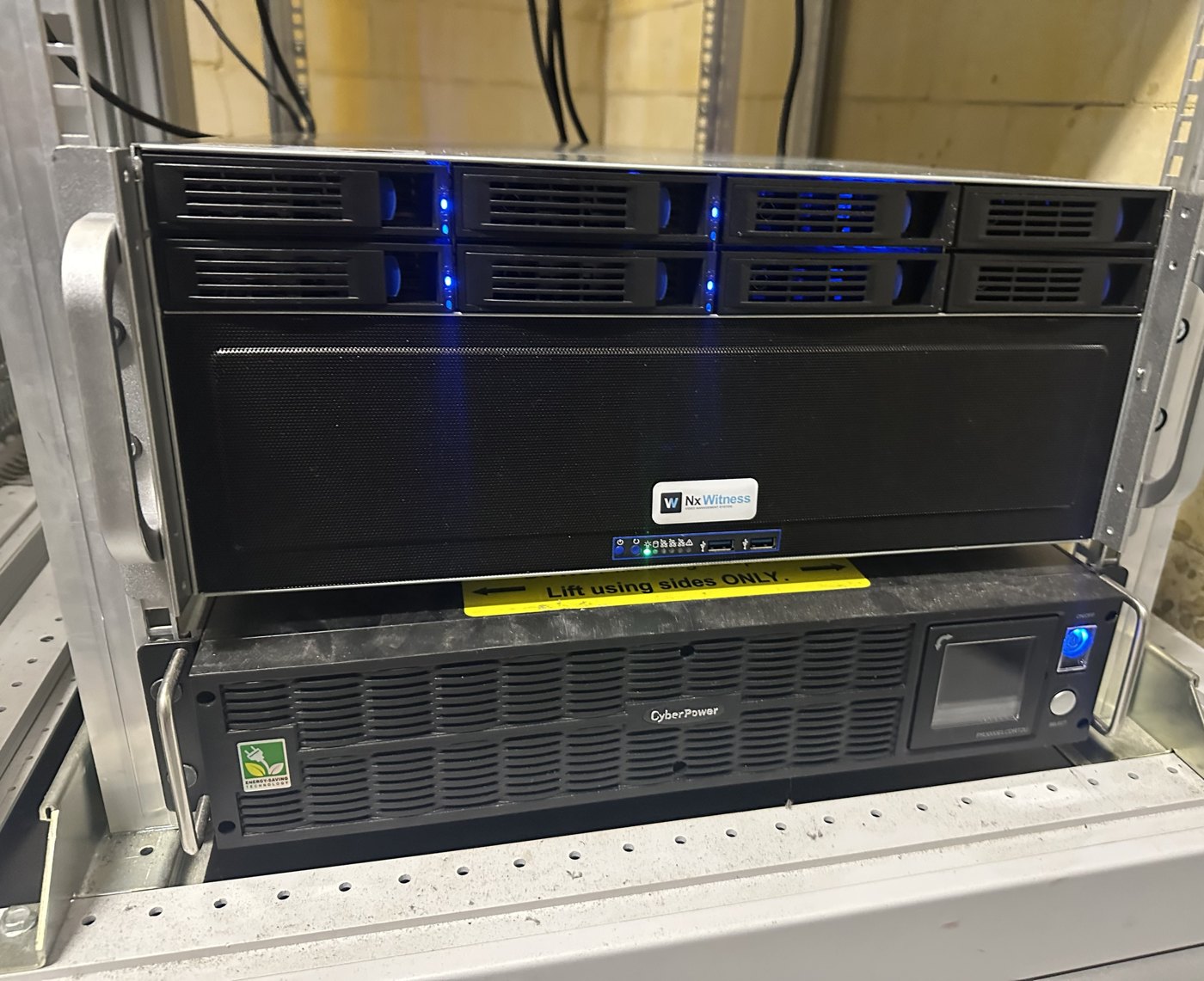 Nx Witness-server met acht schijfladen aan de voorkant en een noodstroomvoeding eronder, in een serverrack