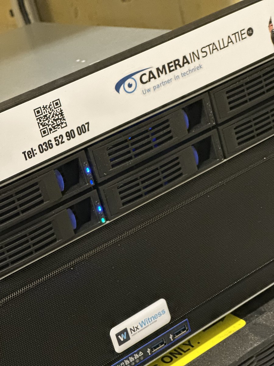 Voorkant van een Nx Witness-server met het label van CameraInstallatie.nl, telefoonnummer en QR-code, en het Nx Witness-schildje