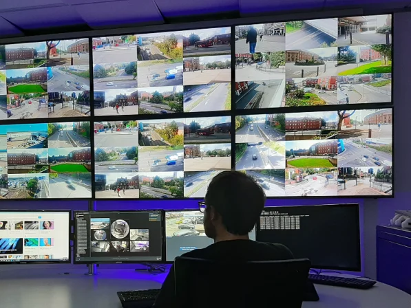 Operator in een meldkamer voor een videowand met camerabeelden